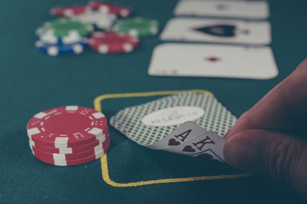 Person holding two playing cards on a poker table. 